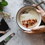 Top view of a yogurt bowl with nuts and berries on a marble table.