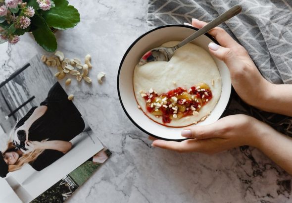 Top view of a yogurt bowl with nuts and berries on a marble table.